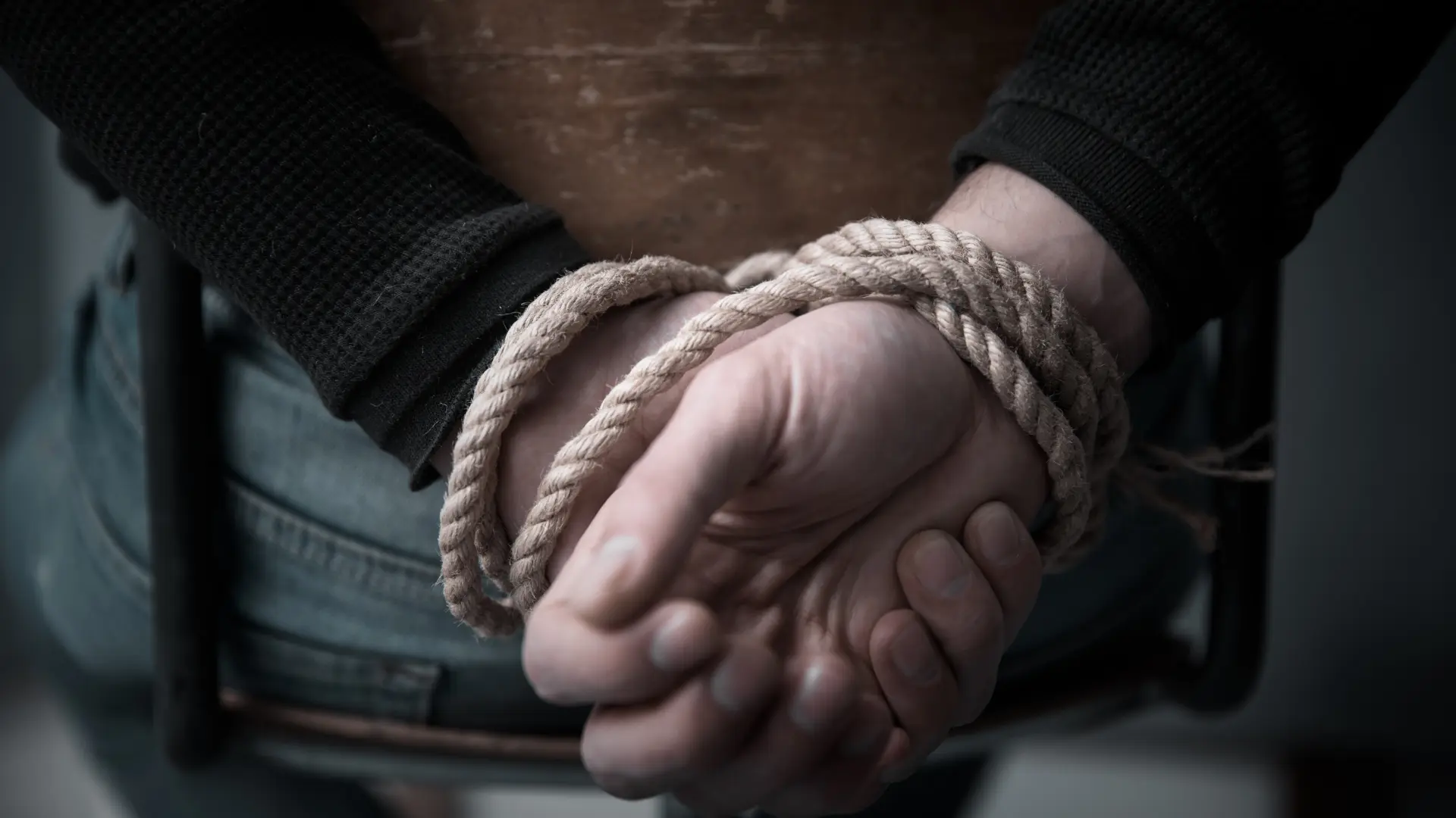 Close-up of a person's hands tied with rope.