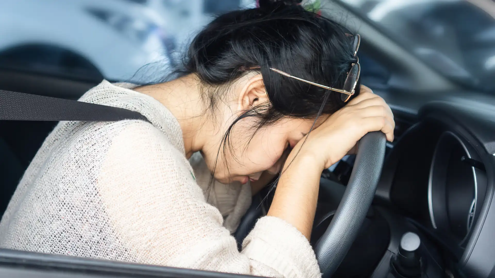 Drunk woman leaning on steering wheel after car accident.