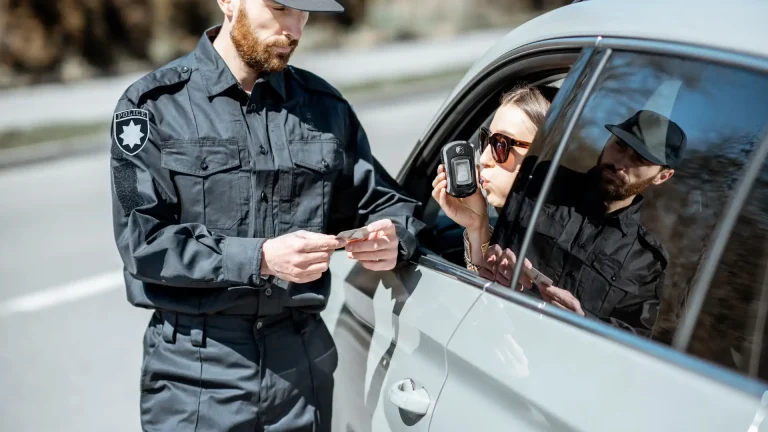 Police officer conducting breathalyzer test on driver