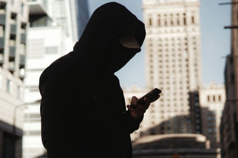 Silhouetted person looking at a phone near a window