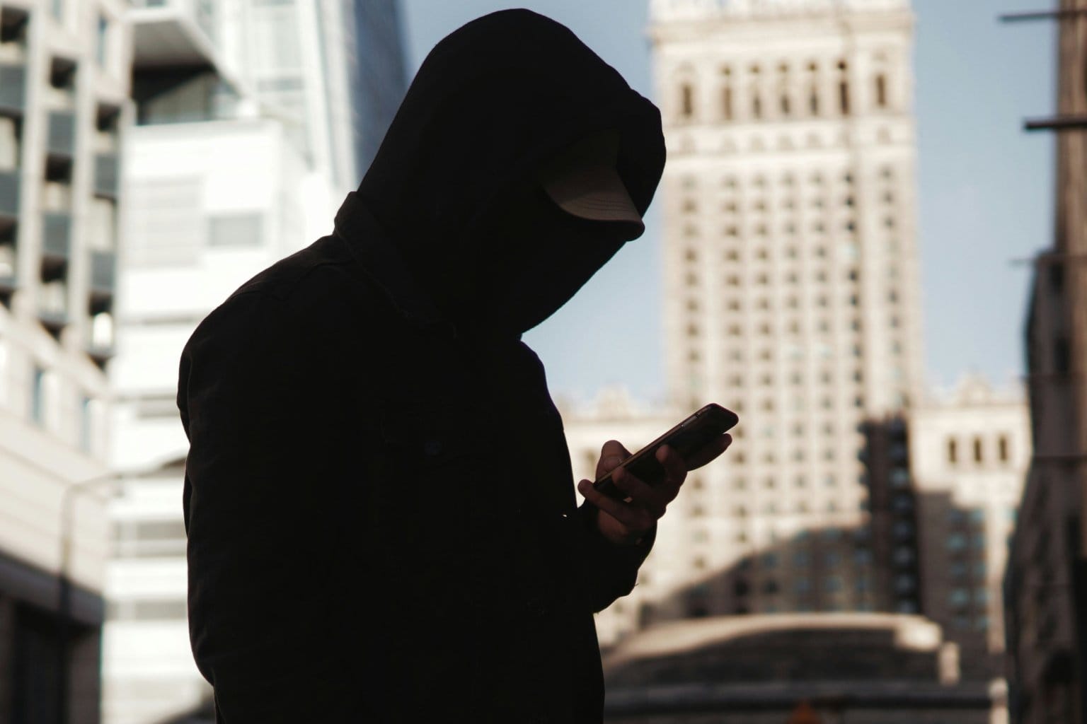 Silhouetted person looking at a phone near a window